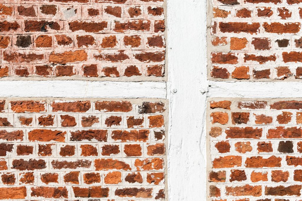 Rote Backsteinwand mit weißem Fachwerk als Detail alter Substanz